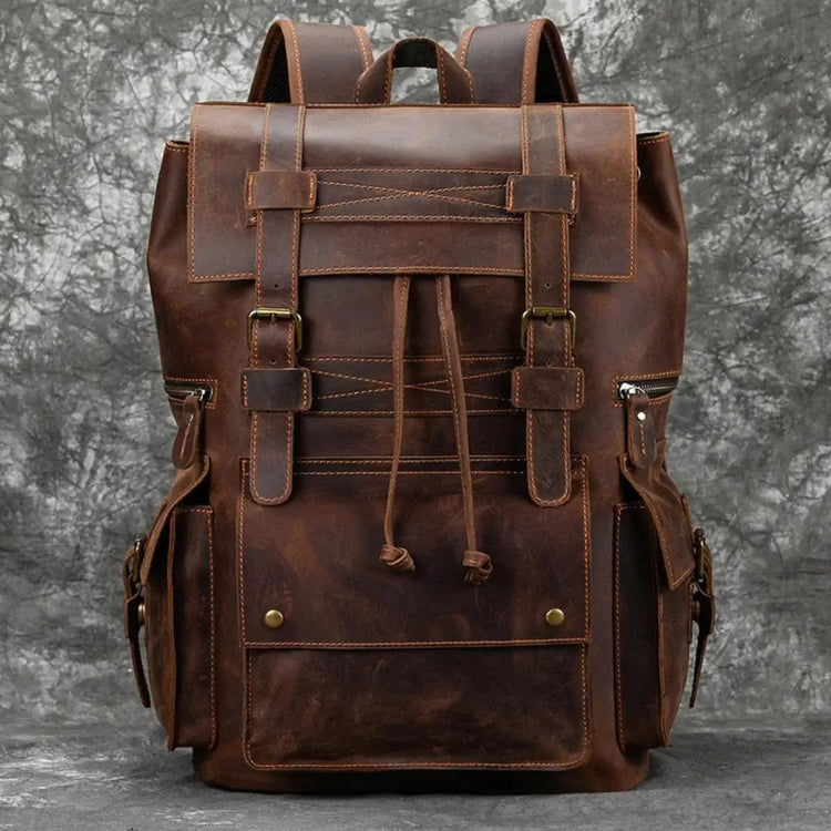Front view of a brown leather backpack with buckle straps and a drawstring closure.