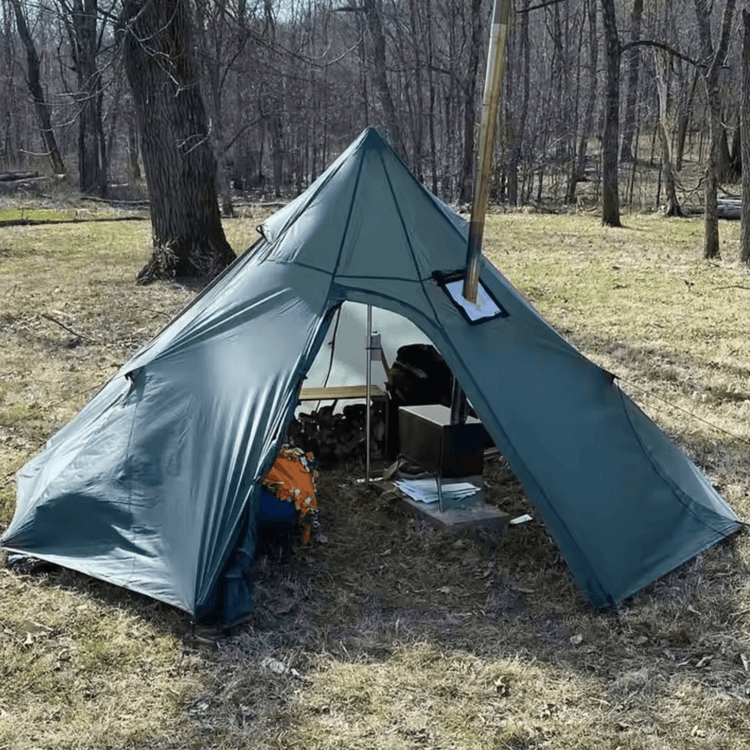 Winter tipi tent for 2-4 campers with stove jack, set in a forest clearing on a sunny day.