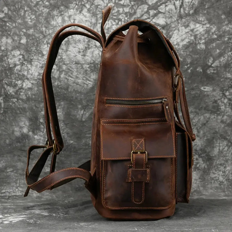 Brown leather backpack with a flap closure, buckle straps, and multiple pockets.