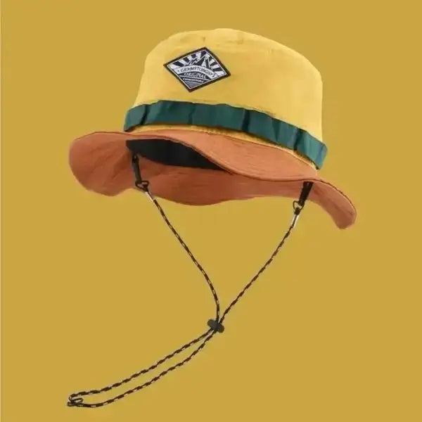 Yellow and orange wide brim bucket hat with green ribbon detail and chin strap, designed for sun protection and outdoor activities.