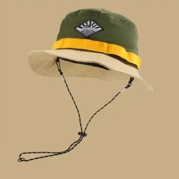 Green and beige bucket hat with wide brim and chin strap on beige background