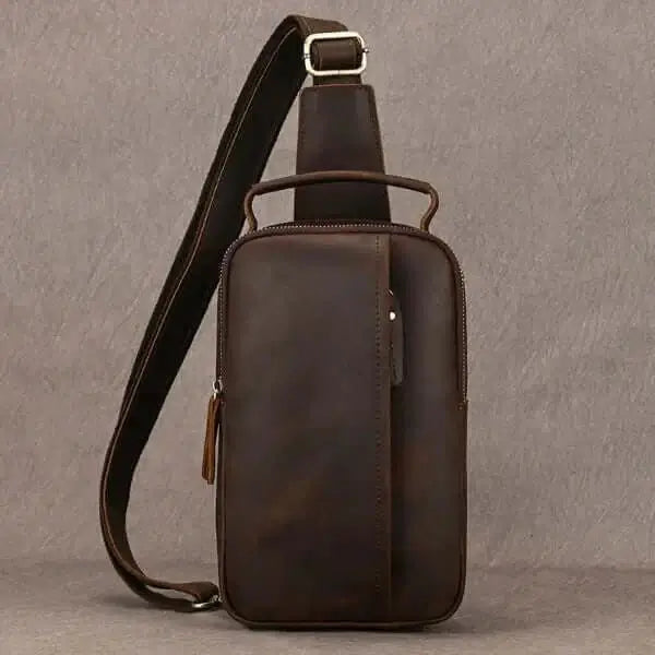 Best sling bag for men, brushed leather, carrying strap, metal buckle, top zipper opening, front view, white background.