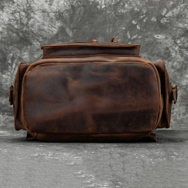 alt="Detailed image of the distressed leather texture on the bottom of a brown backpack."