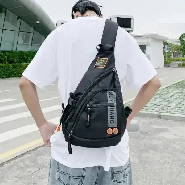Man wearing black crossbody sling bag on back, ideal for travel and daily use, offering durability and water resistance.