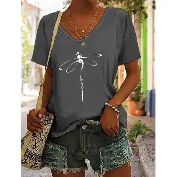 Woman wearing a V-neck graphic tee with a dragonfly design, teamed with distressed denim shorts, perfect for effortless summer style.