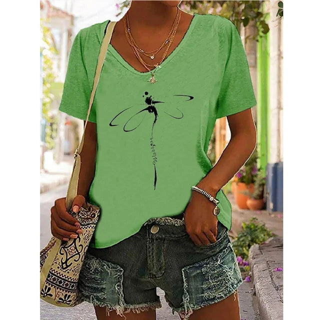 Woman wearing a green V-neck graphic tee with a dragonfly design, teamed with distressed denim shorts, perfect for effortless summer style.