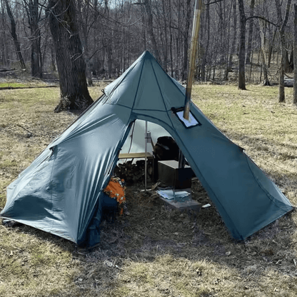 Winter tipi tent for 2-4 campers with stove jack, set in a forest clearing on a sunny day.