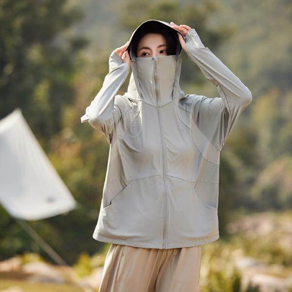 Woman wearing a sun protective hooded jacket with UPF 50+ fabric in a light grey color, perfect for summer outdoor activities.