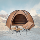 Camping tent with table and chair set against a mountainous landscape