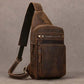  Brown leather crossbody bag with carrying strap, zipper opening, two external pockets, gray background.