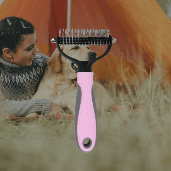 Pink dog grooming brush, background of a woman hugging a Labrador in a tent.