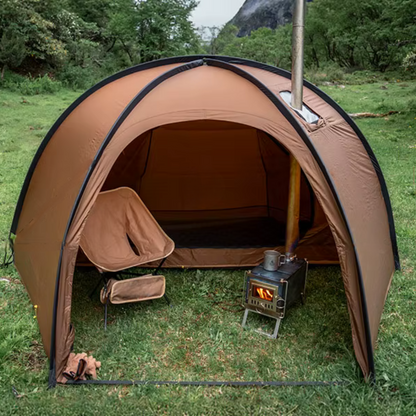 Brown camping tent with a stove and chair in a grassy outdoor setting