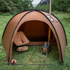 Brown camping tent with a stove and chair in a grassy outdoor setting