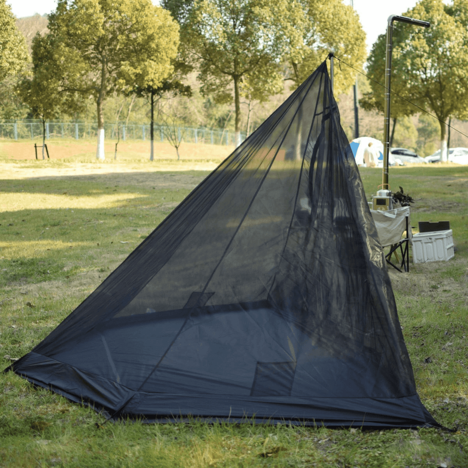 Black inner tent for tipi tent shown on a park with trees and grass in the background.