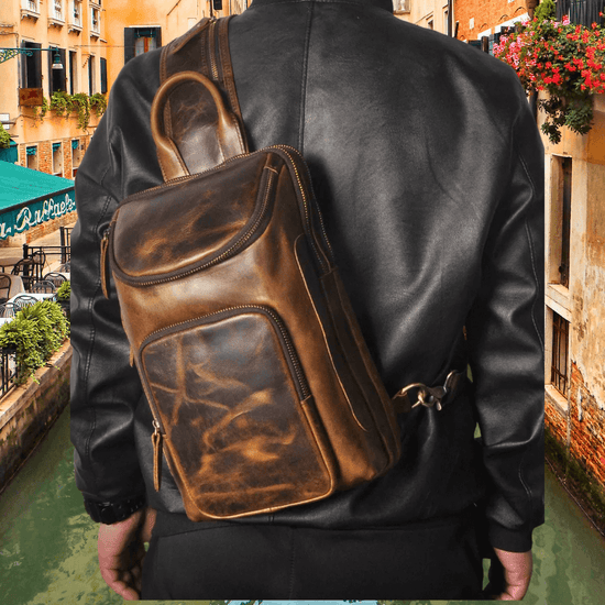 Man wearing leather sling bag in urban setting, showcasing premium cowhide design and durable metal zippers.