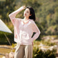 Woman wearing a sun protective pink hoodie jacket with UPF 50+ fabric, enjoying outdoor protection.