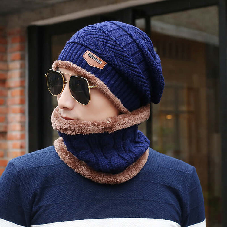 Man wearing a navy blue slouch beanie and matching neck warmer with sunglasses, outdoors in a casual setting.