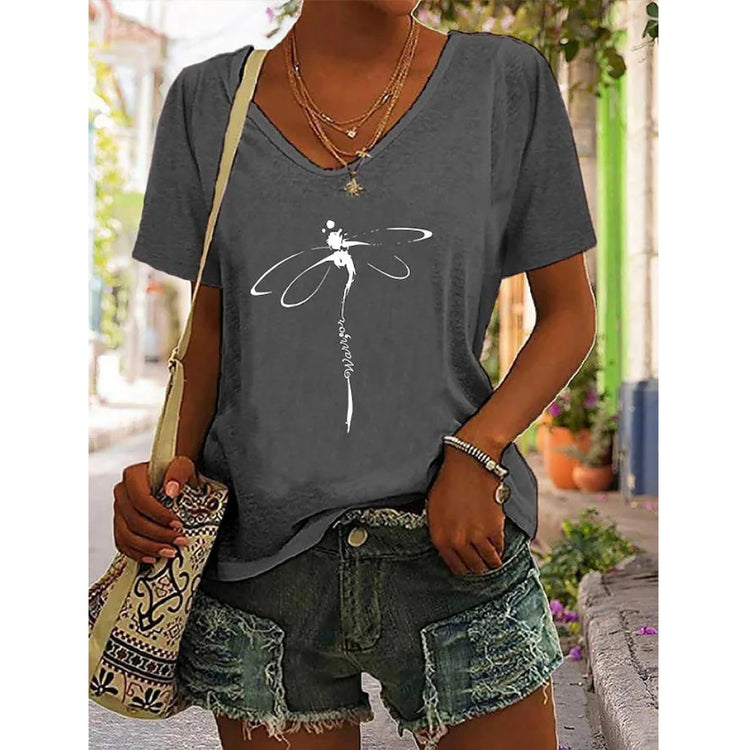 Woman wearing a V-neck graphic tee with a dragonfly design, teamed with distressed denim shorts, perfect for effortless summer style.