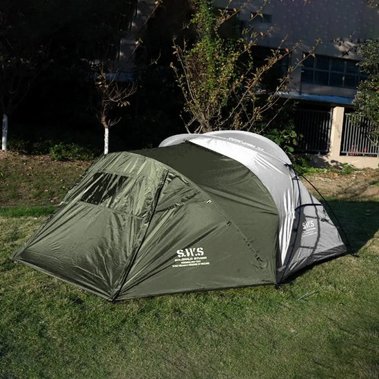 Backpacking tent with stove jack in forest green and gray, shown on green grass with a backdrop of trees. Offers excellent insulation and space for extended camping trips.