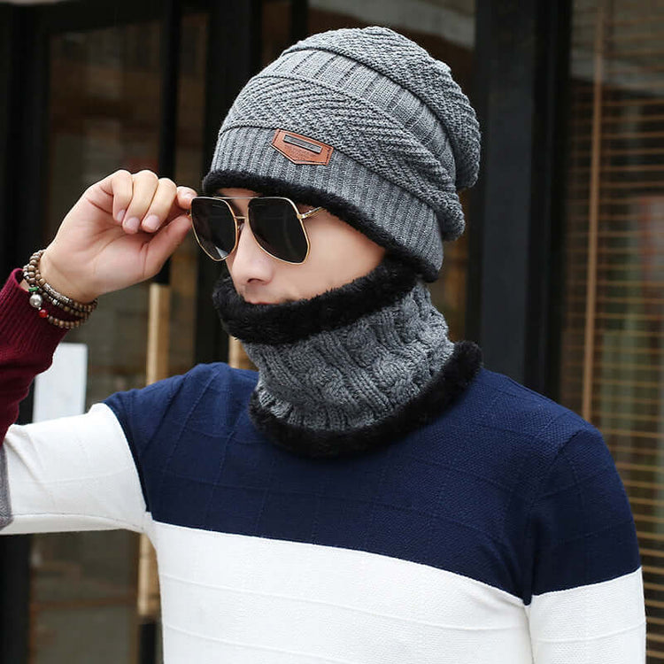 Man wearing a gray wool slouch beanie and matching neck warmer, styled with sunglasses and a color-blocked sweater.