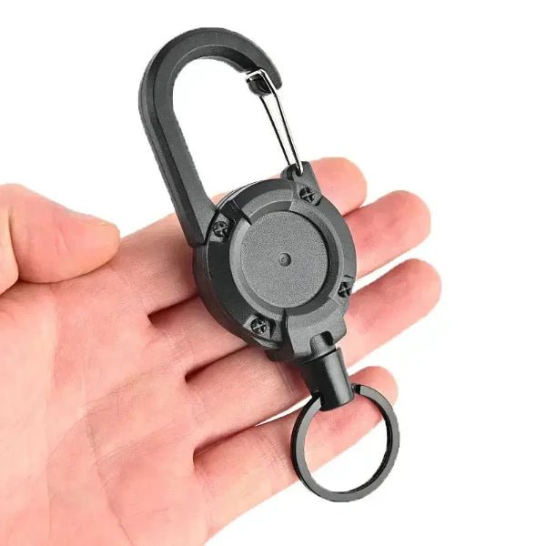 Hand holding anti-theft metal yoyo retractable keychain with strong steel wire cord and durable construction.