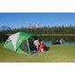 Man inside screened room fixing a fishing rod, mountains and river in the background, teaching a girl to fish.