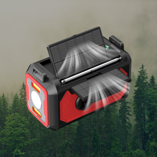 Red radio with solar, electric, and hand crank charging, holding strap, flashlight on, showing solar power charging, forest background.