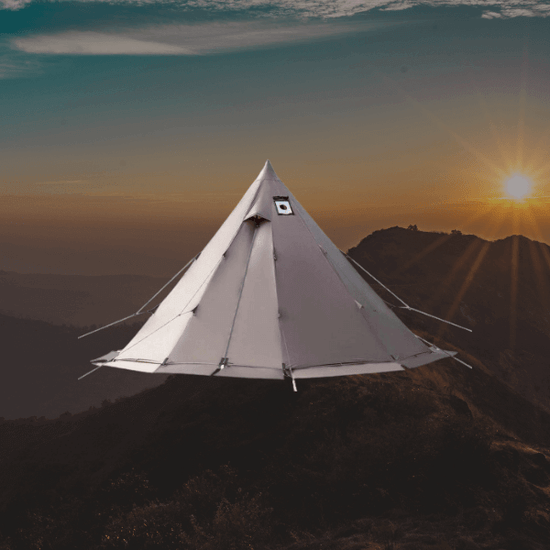 Gray tipi tent with sunset between mountains in the background.