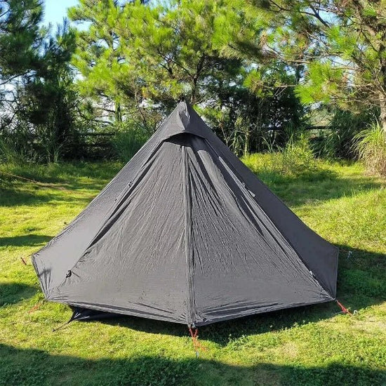 Ultralight black Tipi Pyramid Hot Tent for 1 person in green outdoor setting ideal for winter camping with stove jack.