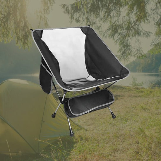 Ultralight folding portable aluminum chair in a scenic camping setting with tent and trees