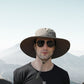 Man wearing gray wide brim safari hat in mountainous outdoor setting