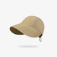 Beige cotton baseball cap held by hand against brick background