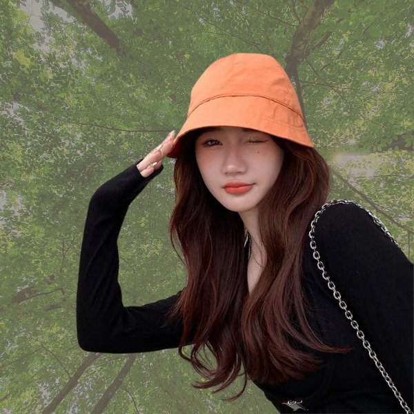 Beige cotton baseball cap held by hand against brick background